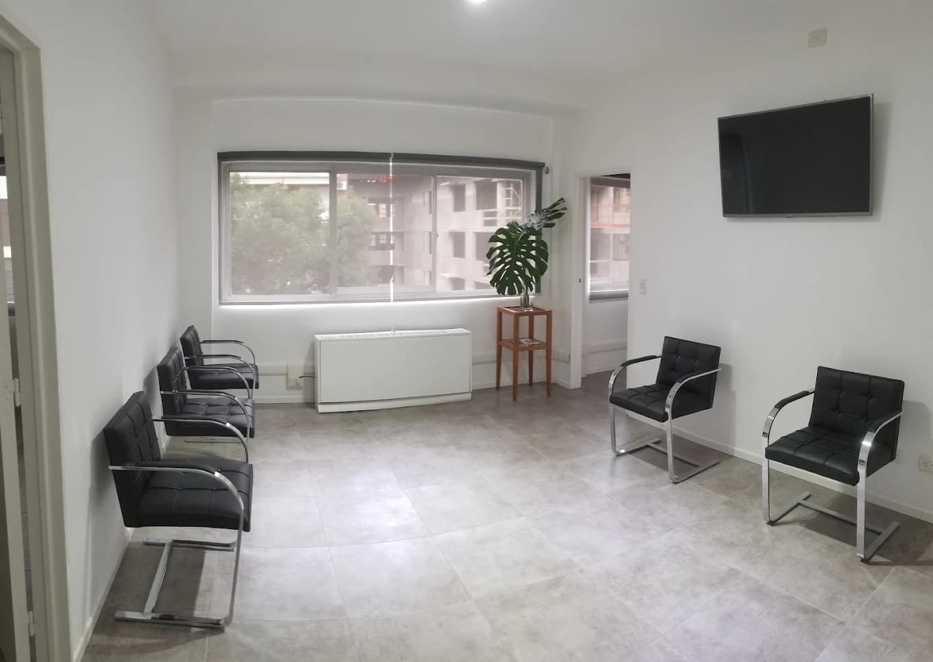 Sala de espera con sillas negras de cromo junto al ventanal